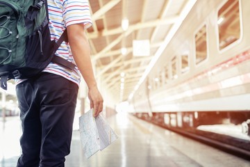 The passengers are stand waiting for the Station platform. Young man traveler with backpack in hand the map looking read with waiting for train. the tourist travel Get ready for departure concept.