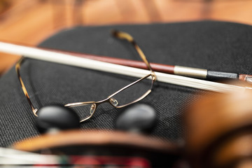 Glasses and a cello bow on a black chair next to a cello © Janisphoto