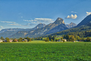 Obraz premium HDR beautiful landscape with lush green grass land and Alpine mountains near Wolfgangsee lake in Austria.