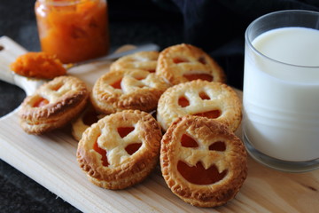 Homemade pumpkin Jam cookie for Halloween with funny faces. Snack with milk.