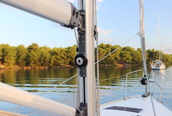 The mainmast is a mast and a twirled staysail on a sailing yacht and bow rails against the backdrop...