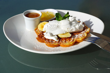 Vegan waffles with fresh banana and coconut cream for breakfast