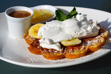 Vegan waffles with fresh banana and coconut cream for breakfast