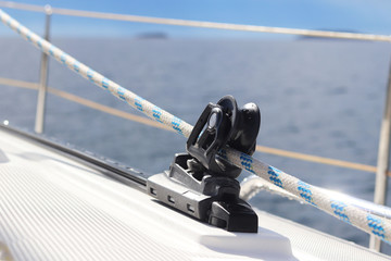 Caretail of a staysaillet on a sailing yacht for sending tracks against the background of the summer sea. Outfit of a sailing yacht. Facilitating human labor on board. Maritime practice of the school.