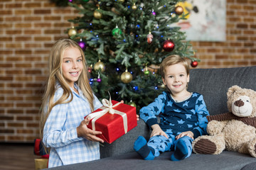 Obraz na płótnie Canvas adorable happy children with christmas present smiling at camera