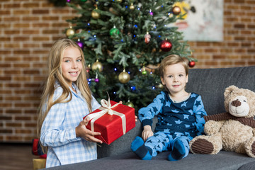 Obraz na płótnie Canvas cute happy children with christmas gift smiling at camera