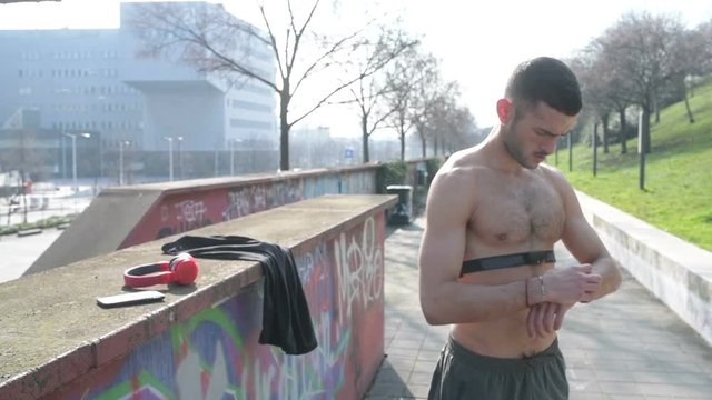 young  man  outdoor  stretching  using  sport  watch  -  preparation,  wereable  technology,  healthy  lifestyle  concept 