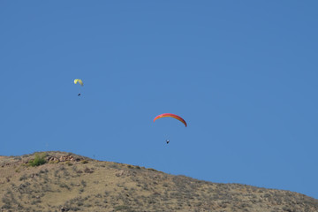 Fototapeta na wymiar Two paragliders gliding off the mountain