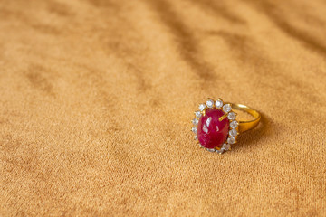 Jewelry red ruby ring on golden fabric background close up