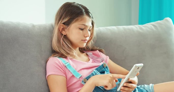 Portrait preteen girl using cell phone in living room