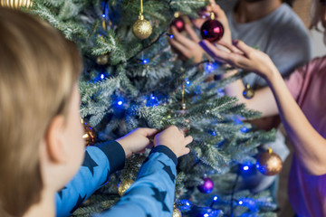 cropped shot of parents with little son decorating christmas tree together