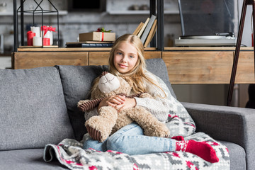 beautiful happy child hugging teddy bear and smiling at camera