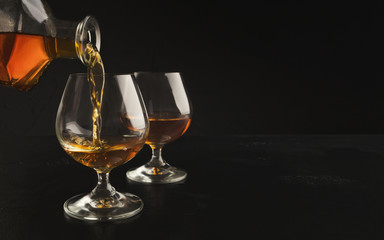 Pouring brandy or cognac from bottle into glass