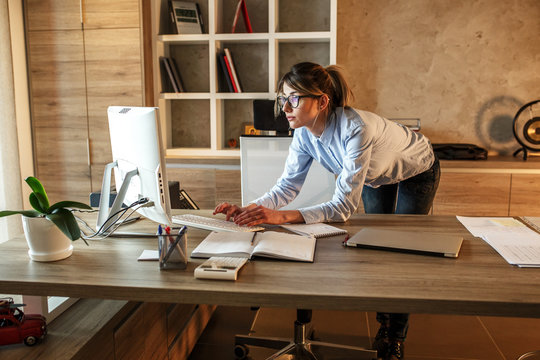 Businesswoman in her office.She sitting at the desk and using computer.