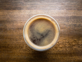 Hot americano coffee on wooden table from top angle close up.