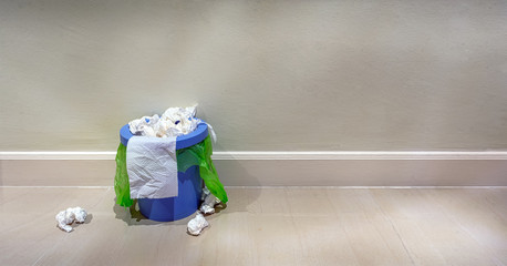 Indoor trash bin overflowing with trash.