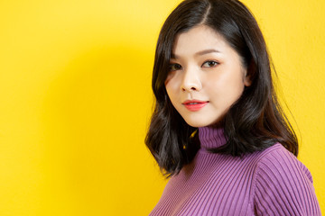 Beautiful Asian women's portrait close up on upper half body on yellow background with a copy space for text and other use.