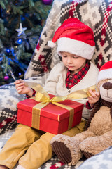 Fototapeta na wymiar adorable little boy in santa hat opening christmas present