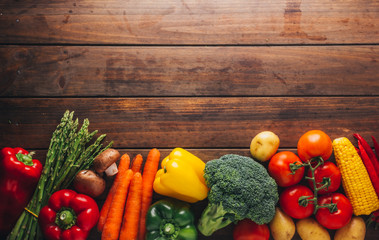 Top view of a wooden table with several types of vegetables in the lower part of the image