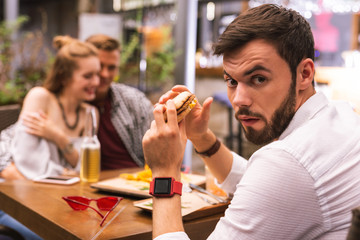 Man with burger. Two people hugging and their friend holding a burger and turning to you