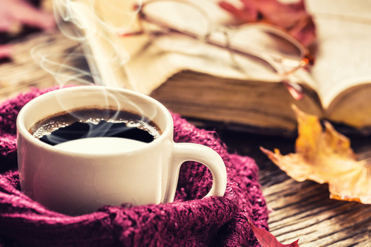 Cup of coffee old  book glasses and autumn leaves.