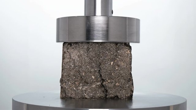 a piece of asphalt road is checked and tested for strength by hydraulic press, close-up