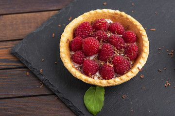 Tartlet with cream and fresh raspberries, served on a slate plate.  Top view.