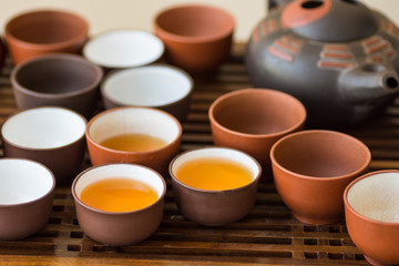 Freshly brewed tea poured in ceramic cups pot utensils on wooden bamboo dripping tray. Chinese Japanese ceremony. Lifestyle local culture. Wellness balance. Poster banner with copy space