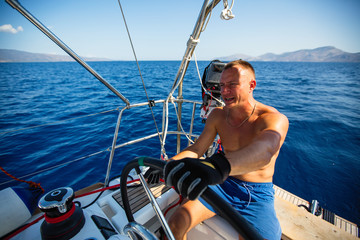 Man at the helm sail boat, the ship controls during sea yacht race.