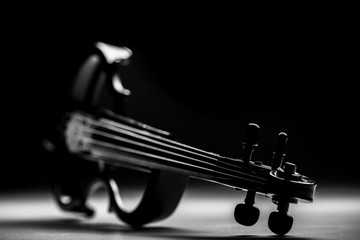 Beautiful black electric violin lying  on a black background
