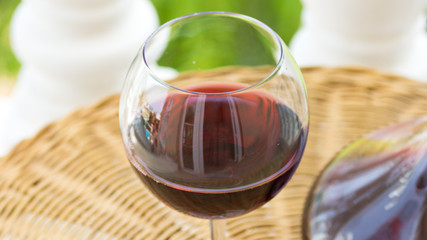 Glass with Red Wine and Crystal Decanter on Wicker Table in Garden Terrace of Luxurious Villa or Mansion. Authentic Lifestyle Image. Relaxation Indulgence Gourmet. Poster