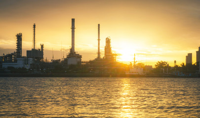 Obraz premium panorama view of petrochemical refinery oil energy plant factory industrial the fuel power storage design on morning skyline with sunshine at golden hour in sky with reflection on water riverside.