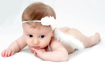 Newborn baby girl posed in a bowl on her back on blanket of fur smiling looking at