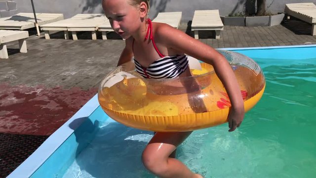 A little boy and a teenage girl frolic in the pool on inflatable circles