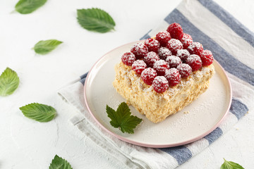 Napoleon cake with raspberries on a white table