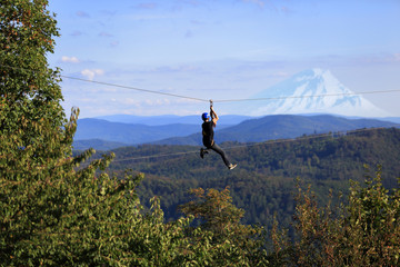 Sporty ekstremalne, mężczyzna zjeżdża na linie zawieszonej nad górami.
