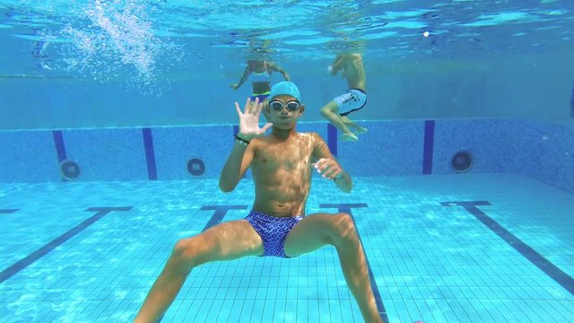 The teenager swims in the pool under the water.