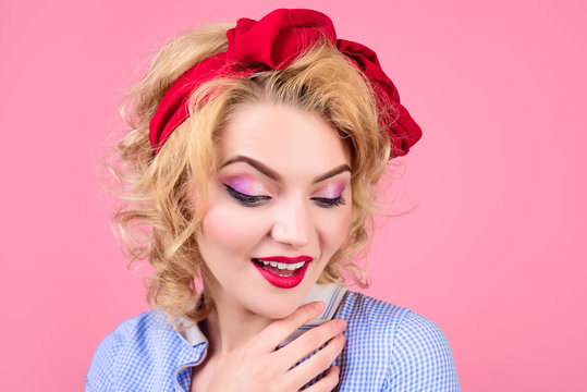 Closeup portrait woman with bright pin up make up. Pin-up clothes. Portrait sensual blonde pin up girl. Woman with bright makeup. Girl with pin-up hairstyle. Retro style. Isolated on pink background.
