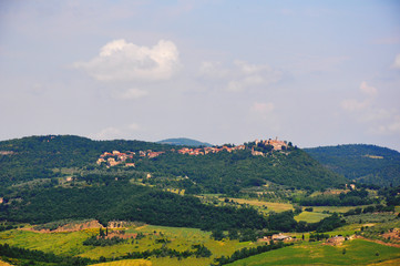 Naklejka premium Distant town in the middle of the fields/hills during a beautiful sunny day in Italy.