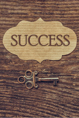 Old antique key and a set of vintage keys and an inscription success on a plate on a wooden background a flat top view, a concept of choosing success and achievements