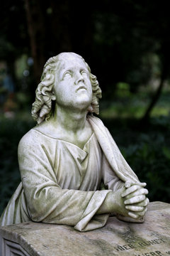 Grabstein mit betender Figur auf einem Friedhof in Frankfurt.