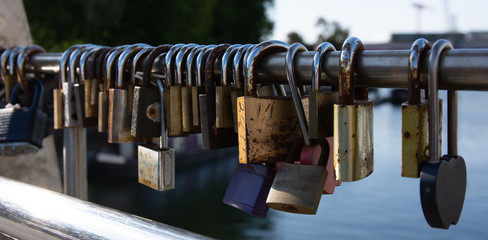 Old rusty padlocks locked to a bridge in a line