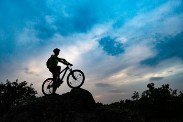 Fototapeta na wymiar Silhouette of Cyclist with Mountain Bike on Rock at Sunset. Extreme Sports and Enduro Cycling Concept.