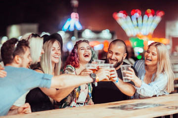 Group of friends drinking beer at music festival. Friends cheering with beer 