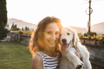 Happy woman with her adorable puppy in a sunset