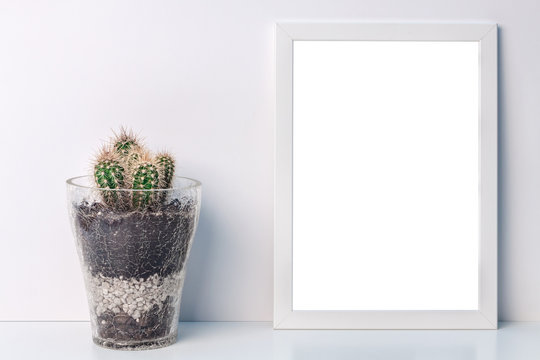 Desk with a white frame mockup with a glass flowerpot with a cactus