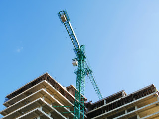 Construction crane against blue sky. Construction site with crane and building.