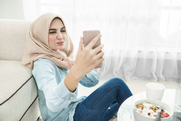 Obraz premium beautiful housewife wearing hijab taking selfies in a leisure ti