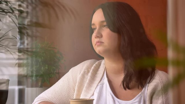 Portrait of big caucasian inert girl holding paper cup and looking in camera