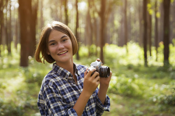 Portrait of Thai-English Girl She is using a camera in the forest.